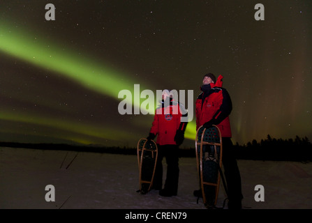 Jeune couple, femme et homme, raquette, regardant tourbillonner le nord de lumières polaires, Aurora Borealis, vert, près de Whitehorse Banque D'Images