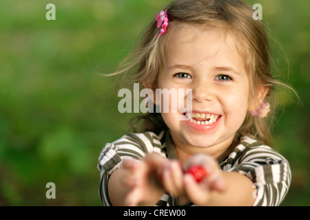 Petite blonde girl picking cherries, Allemagne Banque D'Images