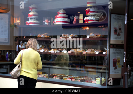 Surrey Angleterre Sutton High Street Femme regardant par la fenêtre de gâteaux Patisserie Valerie Banque D'Images