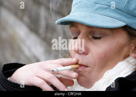 Une femme autour de 40 fumeurs cigerette Banque D'Images