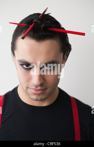 Portrait of smiling young man avec des baguettes dans les cheveux Banque D'Images