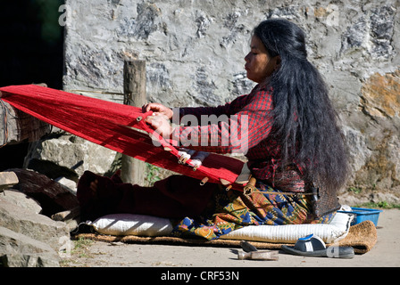 Une femme tribal utilise un métier à l'aide d'un chiffon rouge dans GYASUMDO VILLAGE près de Manang sur le circuit de l'ANNAPURNA, Népal, Katmandou Banque D'Images