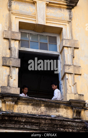 Le Myanmar, Birmanie, Yangon. Deux jeunes hommes en deuxième étages, Colonial-Era bâtiment. Banque D'Images