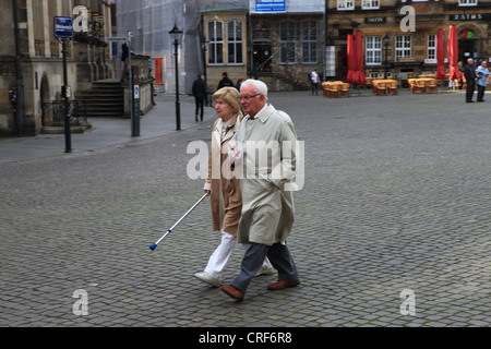 Senior couple marche main dans la main sur la rue place de la ville de Bremen, Allemagne Banque D'Images