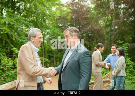 Businessmen shaking hands in forest Banque D'Images