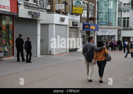 Surrey Angleterre Sutton High Street trois boutiques vides dans une ligne fermée en raison de la récession Couple Walking par Banque D'Images