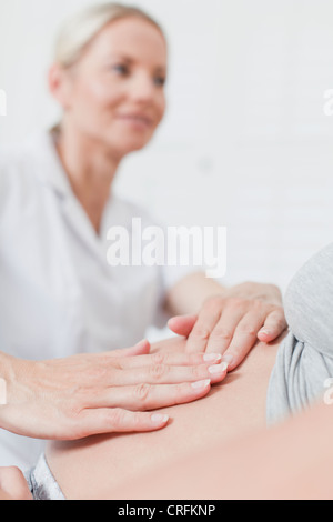 Doctor examining pregnant womans belly Banque D'Images