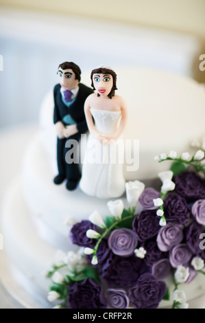 Mariage, UK - petit drôle de minuscules figures humoristiques des mariés sur le gâteau de mariage Banque D'Images