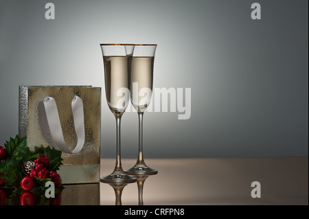 Deux verres de champagne sur une surface d'or décoré avec un sac-cadeau et Holly Banque D'Images