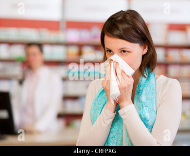 Woman blowing nose en pharmacie Banque D'Images