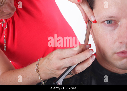 Homme à coiffure. La femelle coiffure utilise un rasoir Banque D'Images