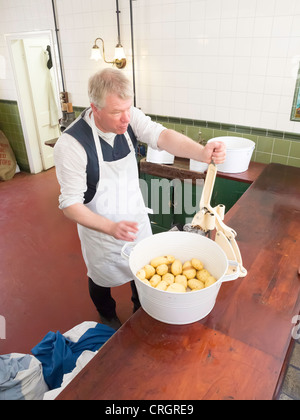 L'homme à l'aide d'un coupe-circuit monté sur banc à Davy's Fish and Chip shop à Beamish Museum of Northern Life Banque D'Images