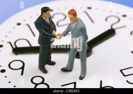 Peu de chiffres sur une horloge shaking hands Banque D'Images