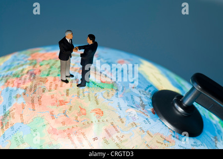 Symbolique pour les relations économiques : peu de chiffres sur un globe shaking hands Banque D'Images