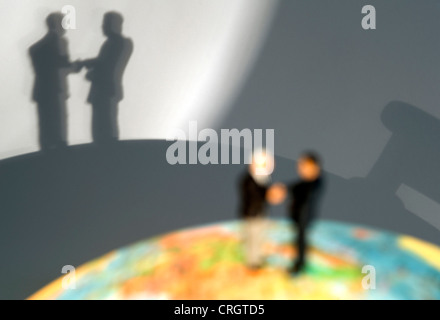 Symbolique pour les relations économiques : peu de chiffres sur un globe shaking hands Banque D'Images