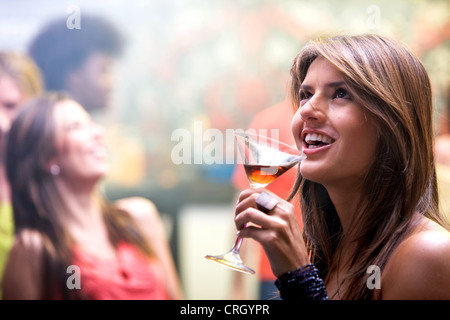 Heureux et souriant femme dans un bar ou une discothèque ayant un verre à cocktail Banque D'Images
