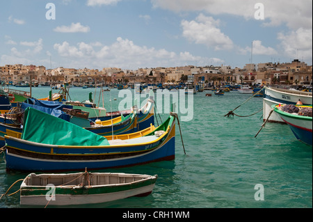 Des bateaux de pêche maltais traditionnels (luzzu) amarrés dans le port dans le village de pêcheurs tranquille de Marsaxlokk, Malte Banque D'Images