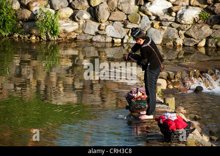 Une femme Miao laver les vêtements à l'xi, de la rivière Xijiang village miao, Chine Banque D'Images