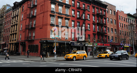 Voir la voiture taxis jaunes gens rouge brique tènements Rainbow Music Store, angle 1e Avenue St Mark's Place, East Village, New York Banque D'Images