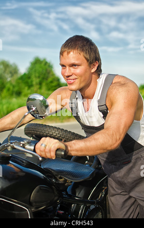 Portrait of handsome mechanic poussant une moto Banque D'Images