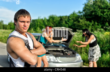 Portrait of a handsome mechanic avec deux femmes sur un arrière-plan Banque D'Images