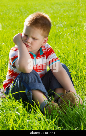 De colère et de tristesse boy sitting on grass Banque D'Images