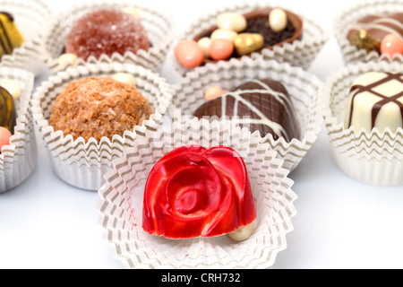 Chocolats Assortis de bonbons dans le panier de papier, gros plan sur un fond blanc Banque D'Images