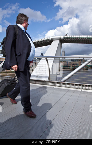 Businessman with Suitcase Crossing Tamise par Millennium Bridge sur Sunny Day Banque D'Images