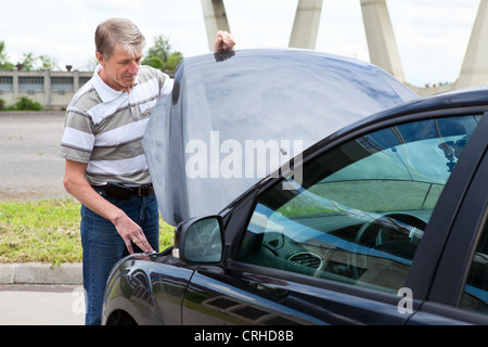 Homme mûr ouvre un capot de voiture pour réparer sa voiture en panne Banque D'Images