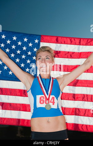 Médaille femme holding up drapeau américain dans la victoire Banque D'Images