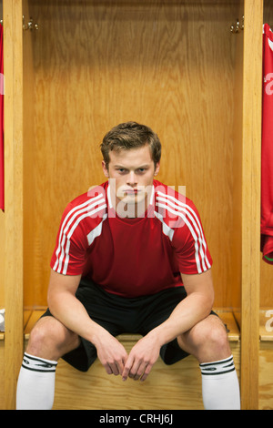 Joueur de foot assis dans le vestiaire Banque D'Images