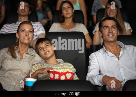 Family enjoying movie, boy resting head sur l'épaule de sa mère Banque D'Images