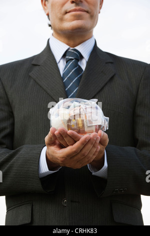 Man holding piggy bank transparente remplie d'euros Banque D'Images