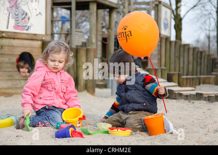 Les jeunes avec des moules de sable à l'aire de jeux pour enfants Banque D'Images