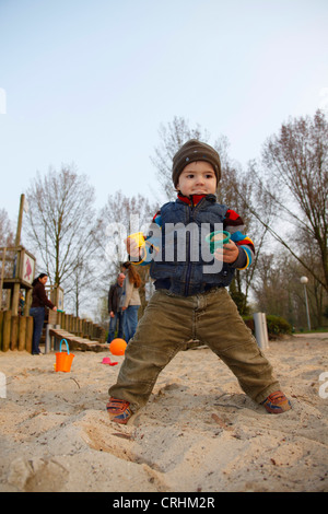 Petit garçon à l'aire de jeux pour enfants, adultes à l'arrière-plan Banque D'Images