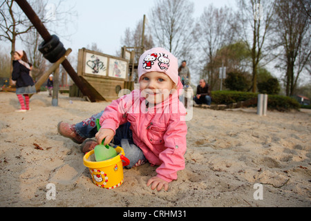 Fille avec des moules de sable à l'aire de jeux pour enfants Banque D'Images