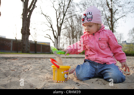 Fille avec des moules de sable à l'aire de jeux pour enfants Banque D'Images