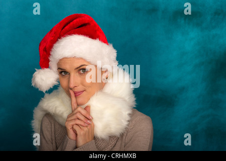 Woman wearing Santa hat, collés sur des lèvres, portrait Banque D'Images