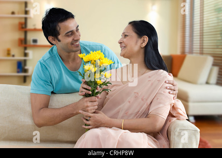 Man giving mère bouquet de fleurs à la maison Banque D'Images