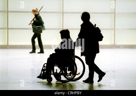 Silhouettes d'une femme qui met l'autre dans un fauteuil roulant Banque D'Images