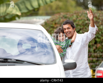 Père et fils en souriant avec une voiture à l'extérieur, prêt à démarrer en vacances Banque D'Images