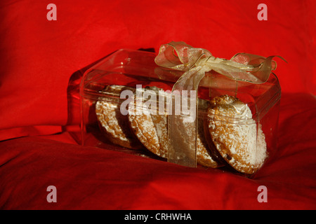 Case transparent de tartes hachée enveloppée de ruban sur cusion rouge. Banque D'Images