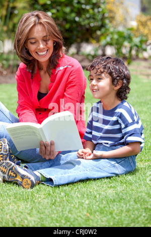 La mère et le fils assis sur une pelouse, la lecture d'un livre ensemble Banque D'Images