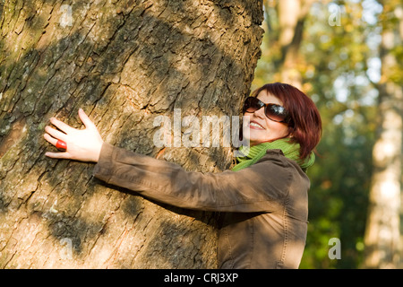 Jeune femme en automne embrassant un tronc d'arbre Banque D'Images
