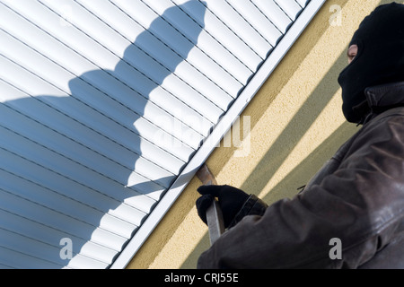 Housebreaker en utilisant des mots de la backdoor, debout en face de jalousie fermé Banque D'Images