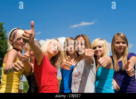 Group of smiling teenage girls standing in a row tourner le pouce vers le haut Banque D'Images