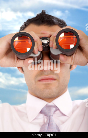 Businessman looking through binoculars outdoors Banque D'Images