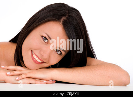 Smiling young girl avec la tête posée sur ses bras Banque D'Images