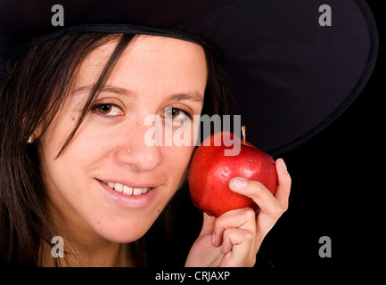 Jeune fille avec un chapeau de sorcière tenant une pomme rouge Banque D'Images