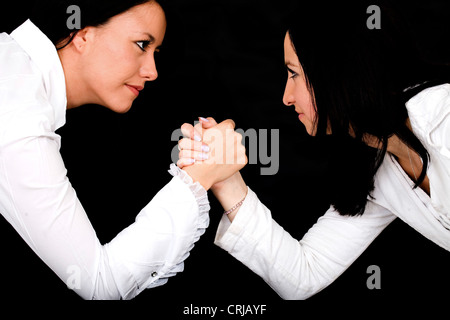 Deux jeunes femmes aux cheveux noirs avec des blouses blanches Arm wrestling Banque D'Images